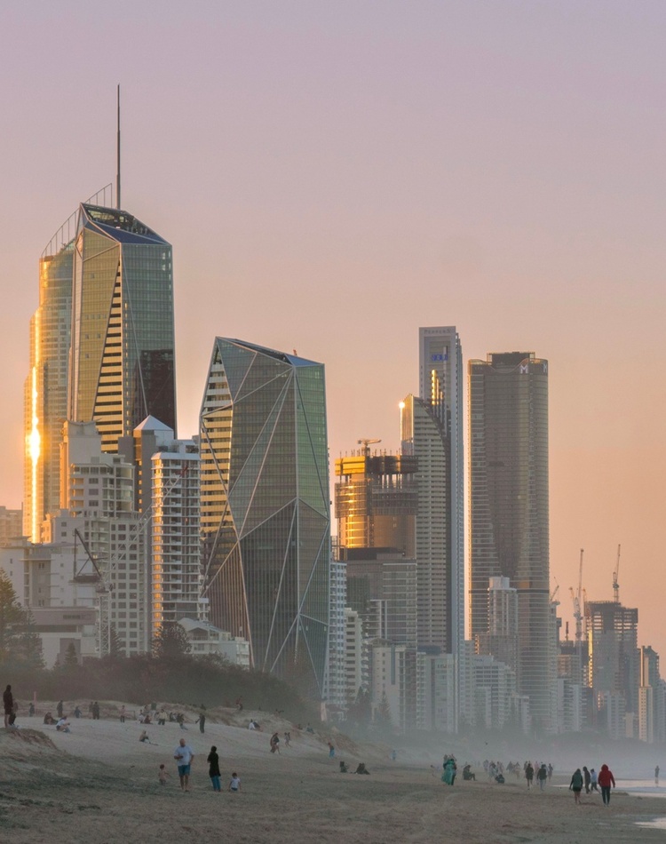 An eroded beach with skyscrapers in the background on the coastal fringe.