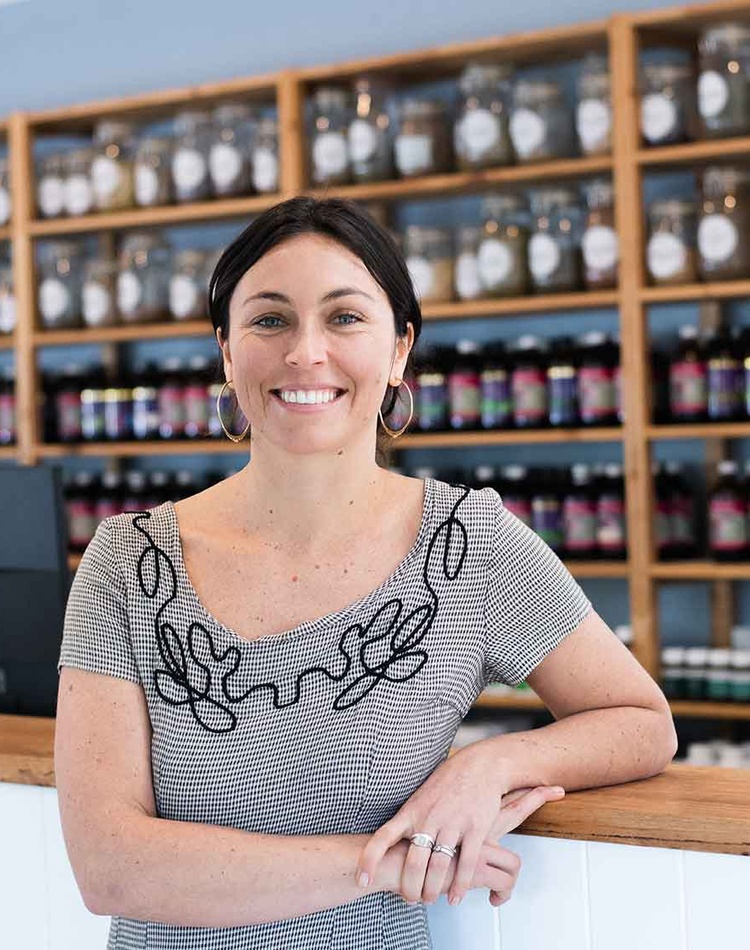 Naturopath stands in front of dispensary counter