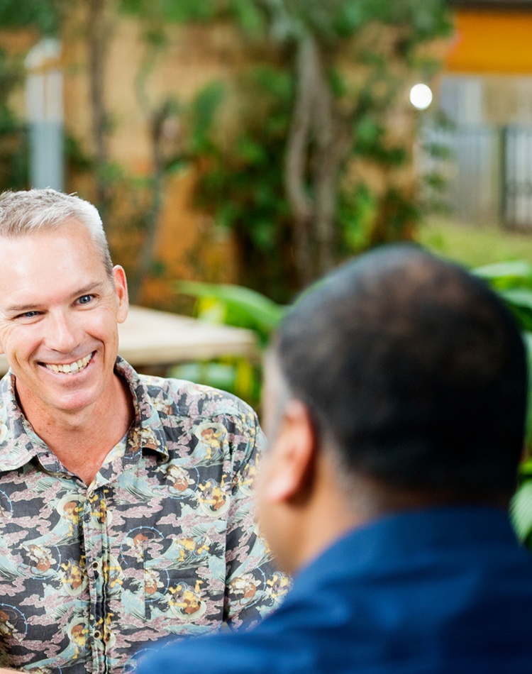 fair haired man smiling at person with back to screen