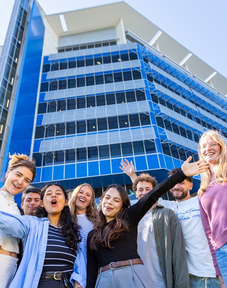 students with hands out in welcome standing in front of a Gold Coast campus building