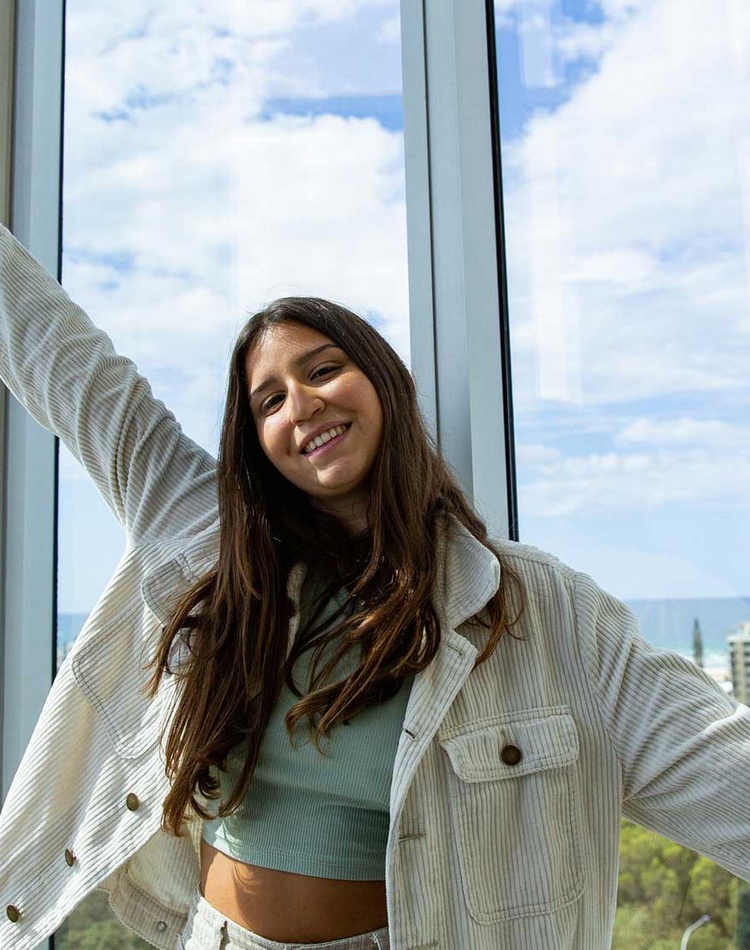 A student in front of a window at the gold coast campus