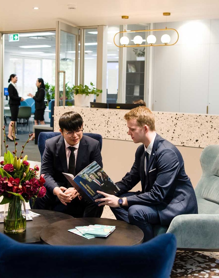 Two male Tourism and Hotel Management students sit in the foyer of The Hotel School - Melbourne.
