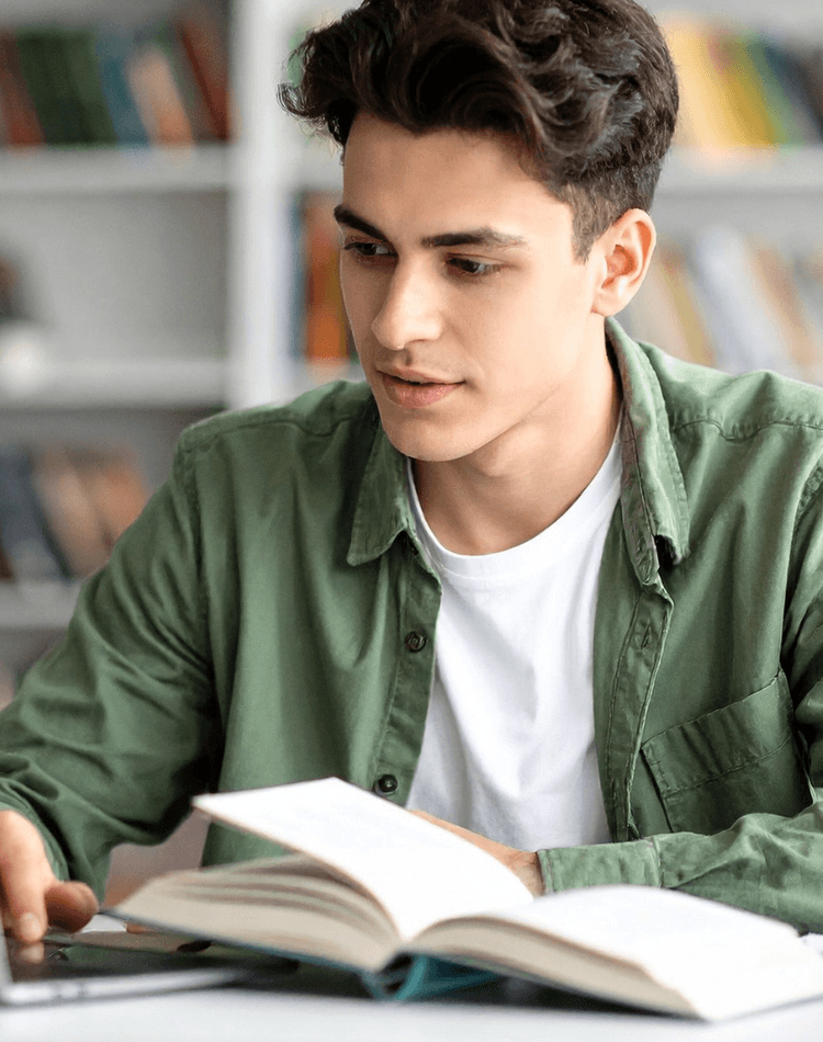 Student reading textbook and working on laptop - postgrad events banner