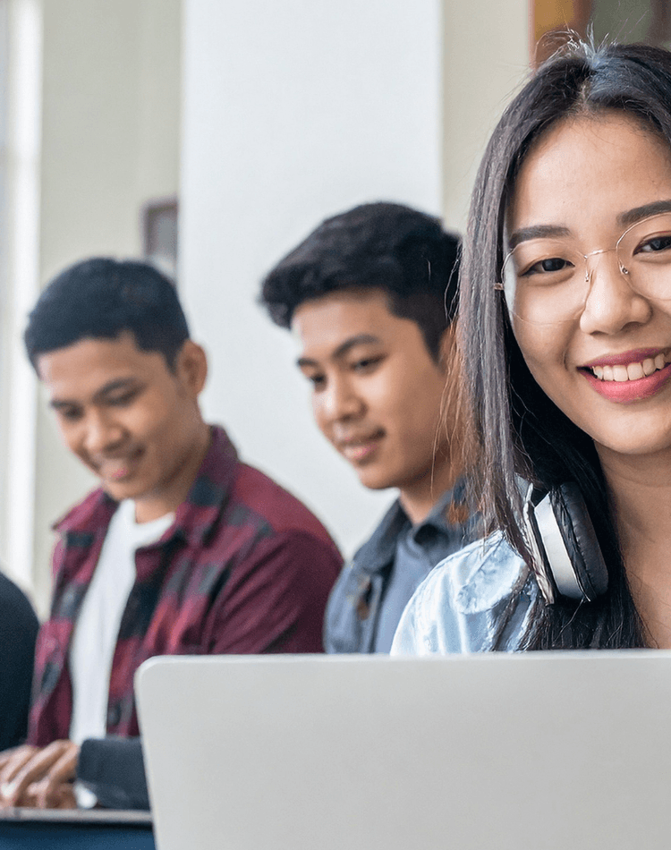 A group of smiling international students working on laptops - for postgrad workshop events