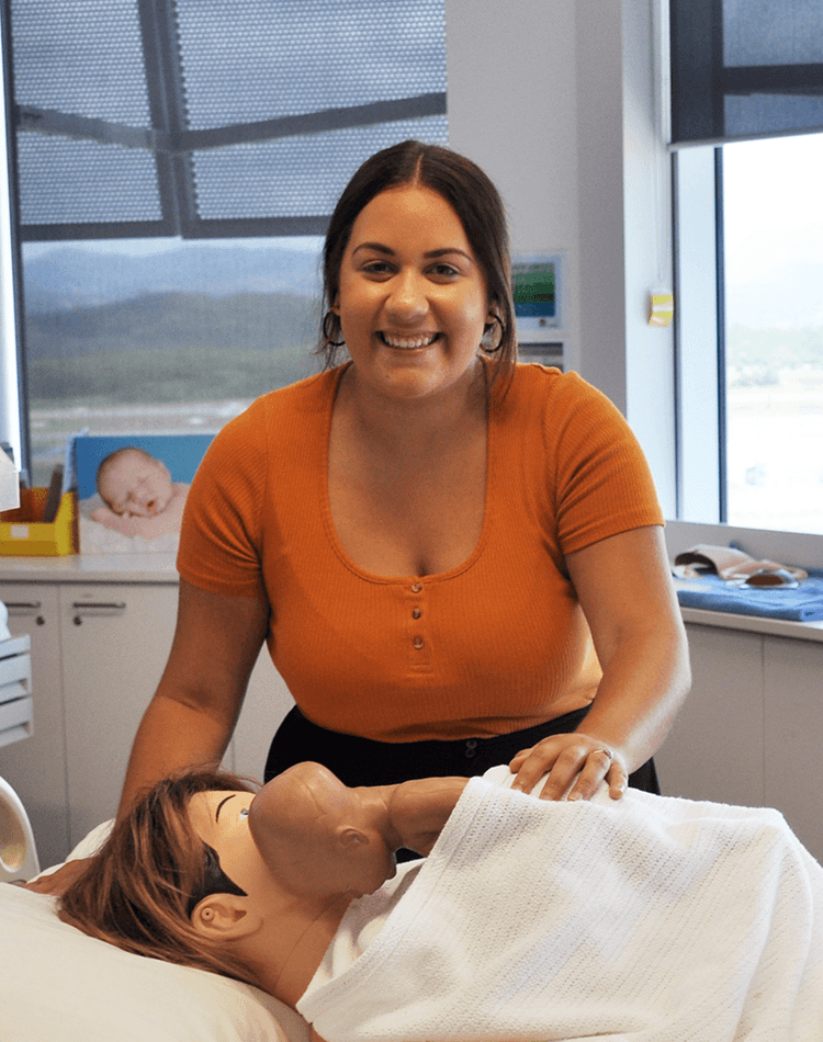 Midwifery graduate Taneeka Thomas in health lab with dummy patient and baby