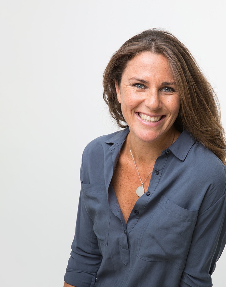 Headshot of woman smiling with blue long sleeve shirt and necklace