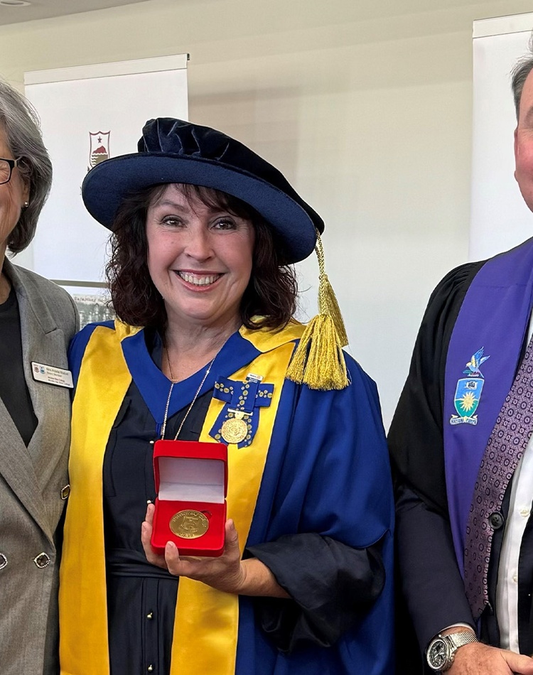 Women in academic dress with medal standing between woman and man