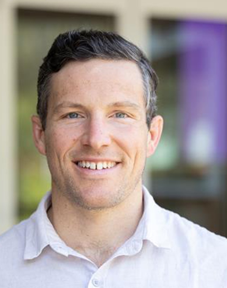 Headshot of man in button up shirt smiling at camera