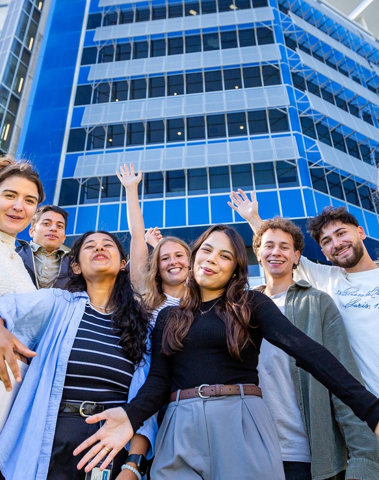 Group of students posing in front of blue building