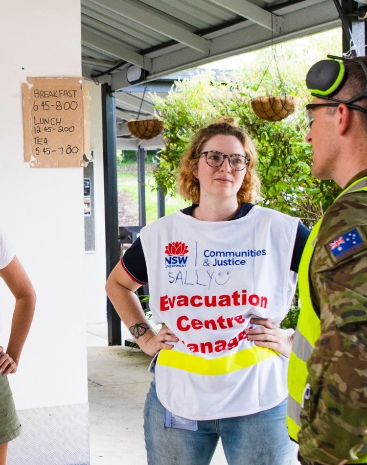 Two women and a man talking in front of a temporary emergency canteen
