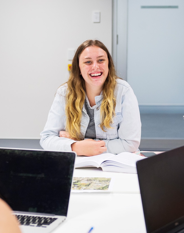 Student smiling in group with laptops
