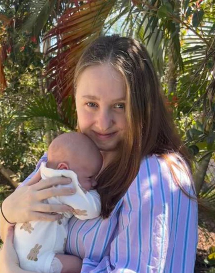 Brittany Elliott faces camera cuddling her baby