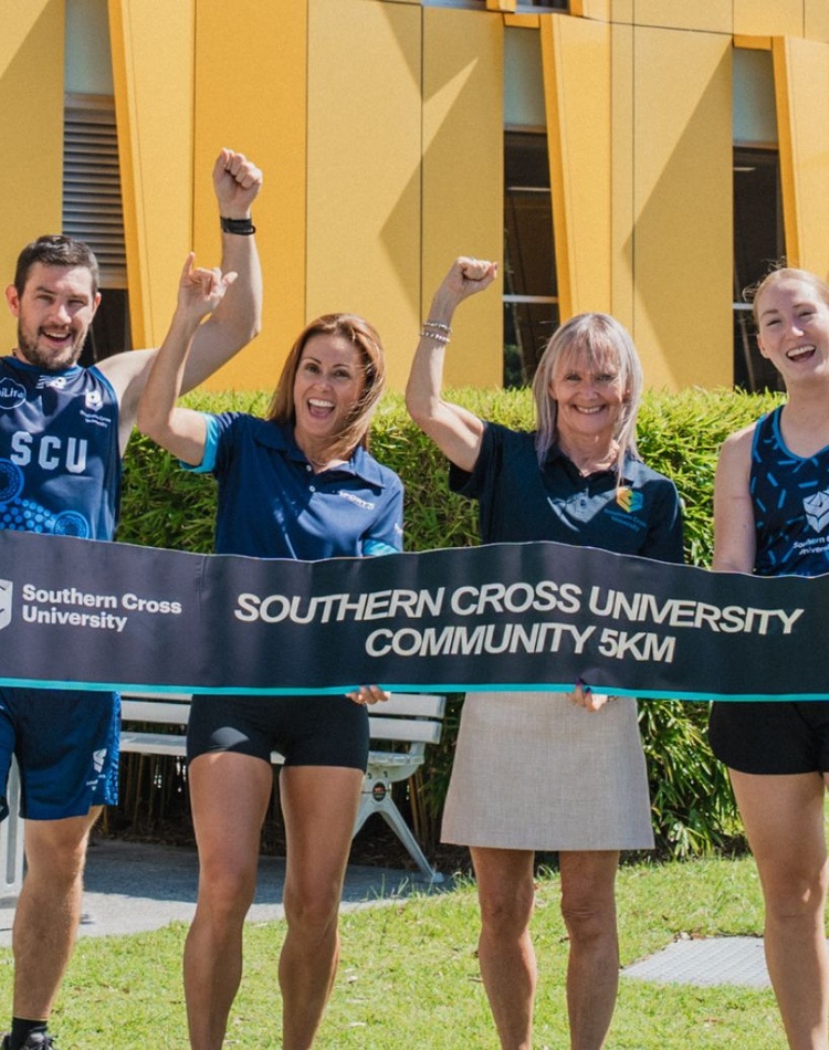 A group of people hold a banner advertising the GC50 Run Festival