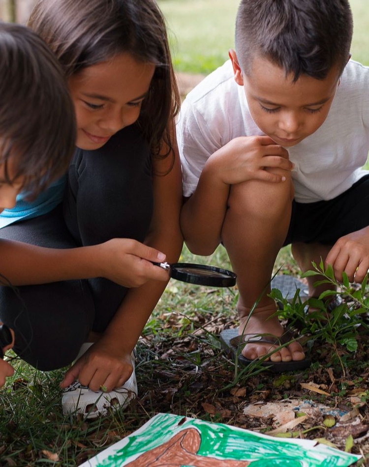 three children look through a magnifying glass