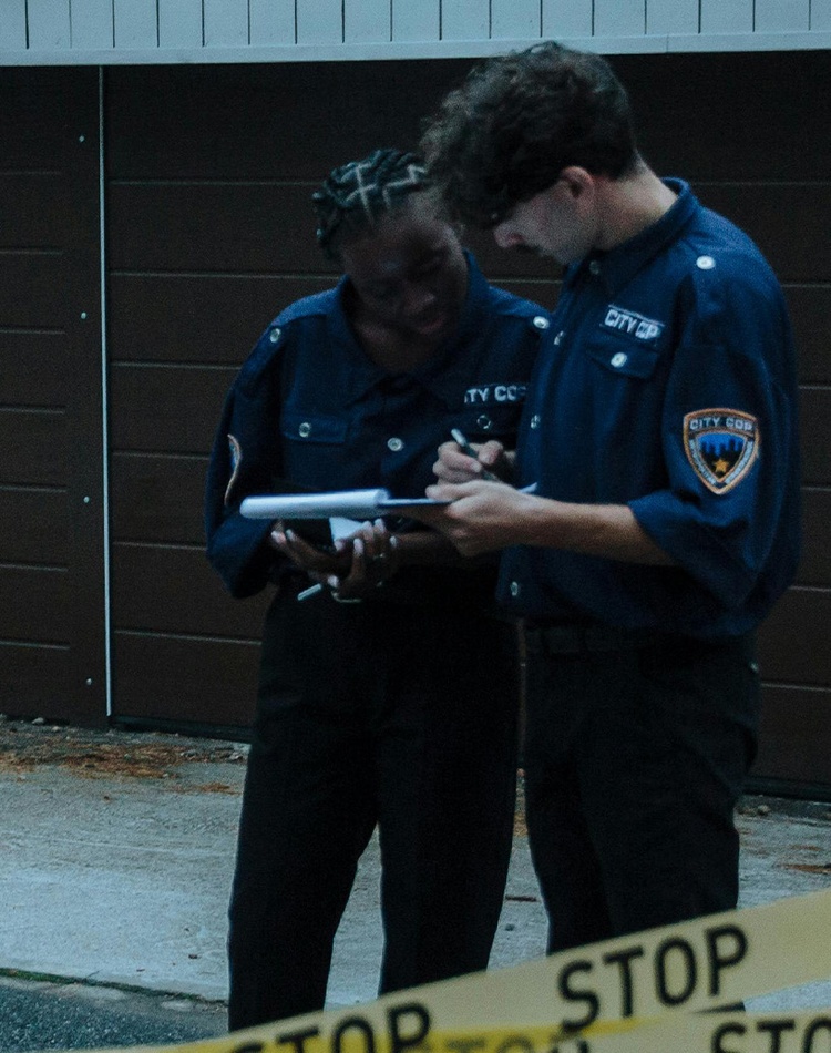 American police looking at clipboard in front of police tape