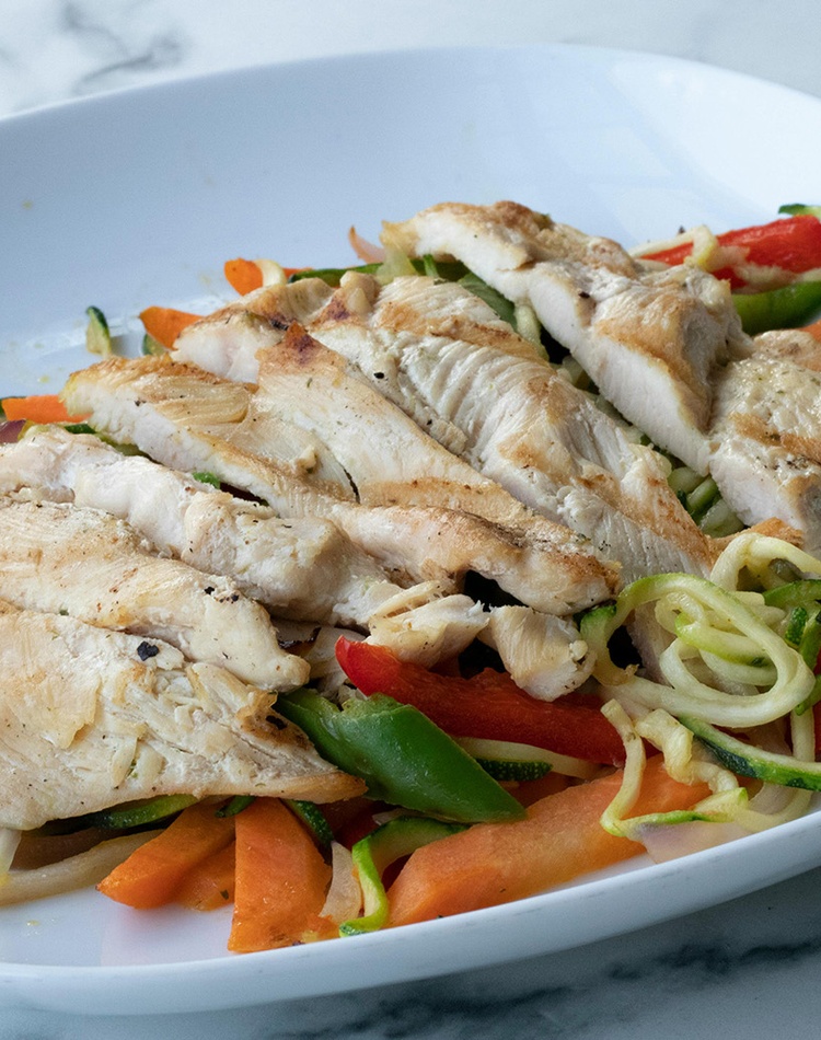 Sliced chicken breast on plate of mixed vegetables