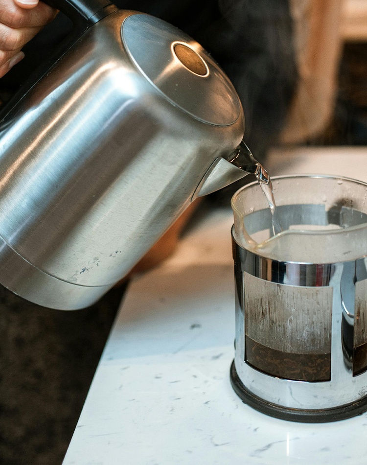Boiling water poured from kettle into coffee plunger