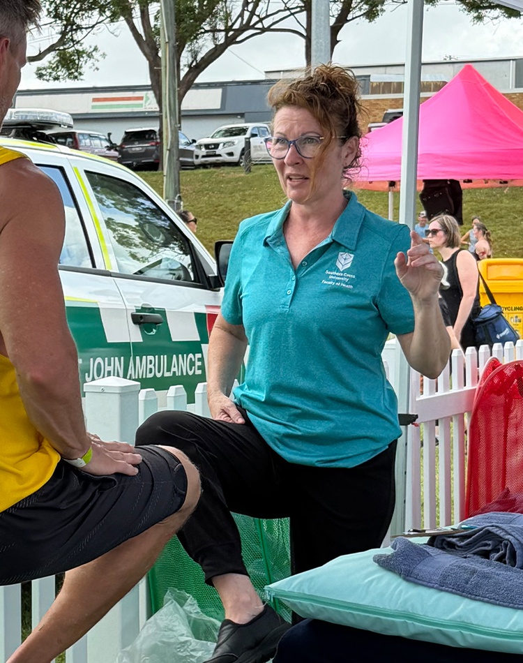 Health student working with athlete, both lifting one leg