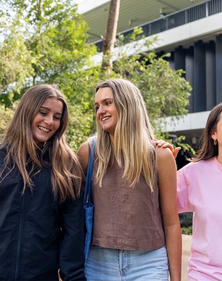 Three female students smiling in front of learning centre