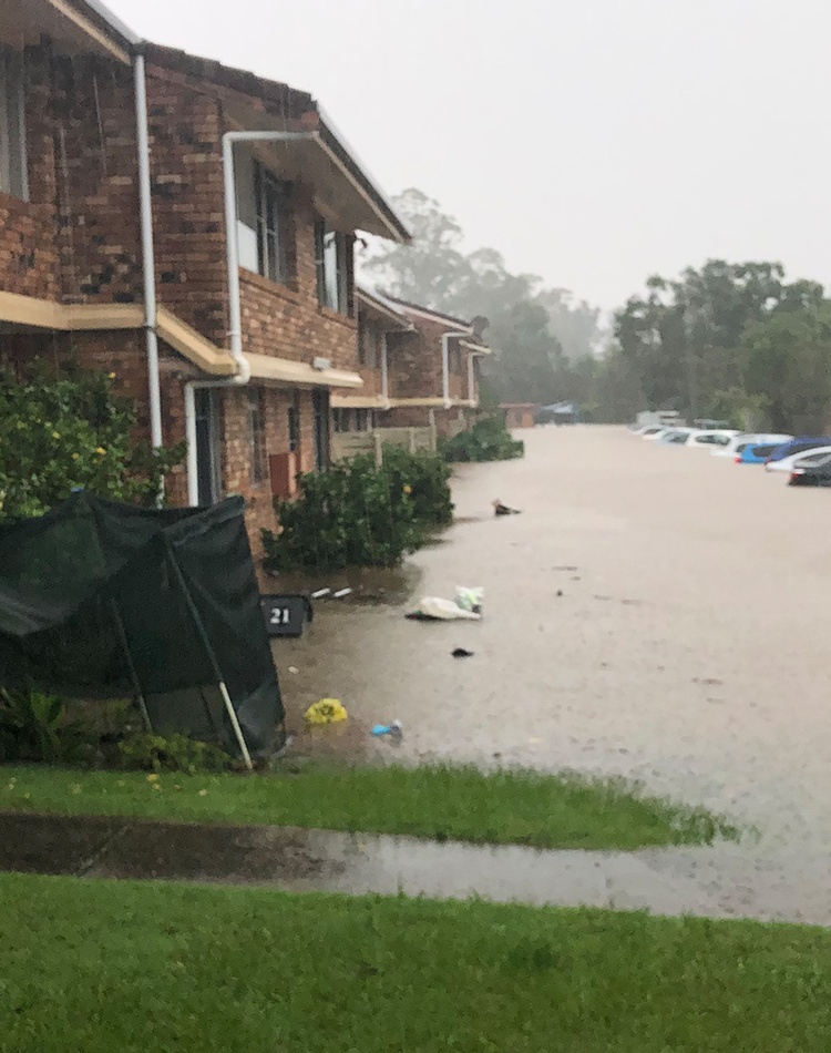 A flooded street with unit blocks and cars underwater