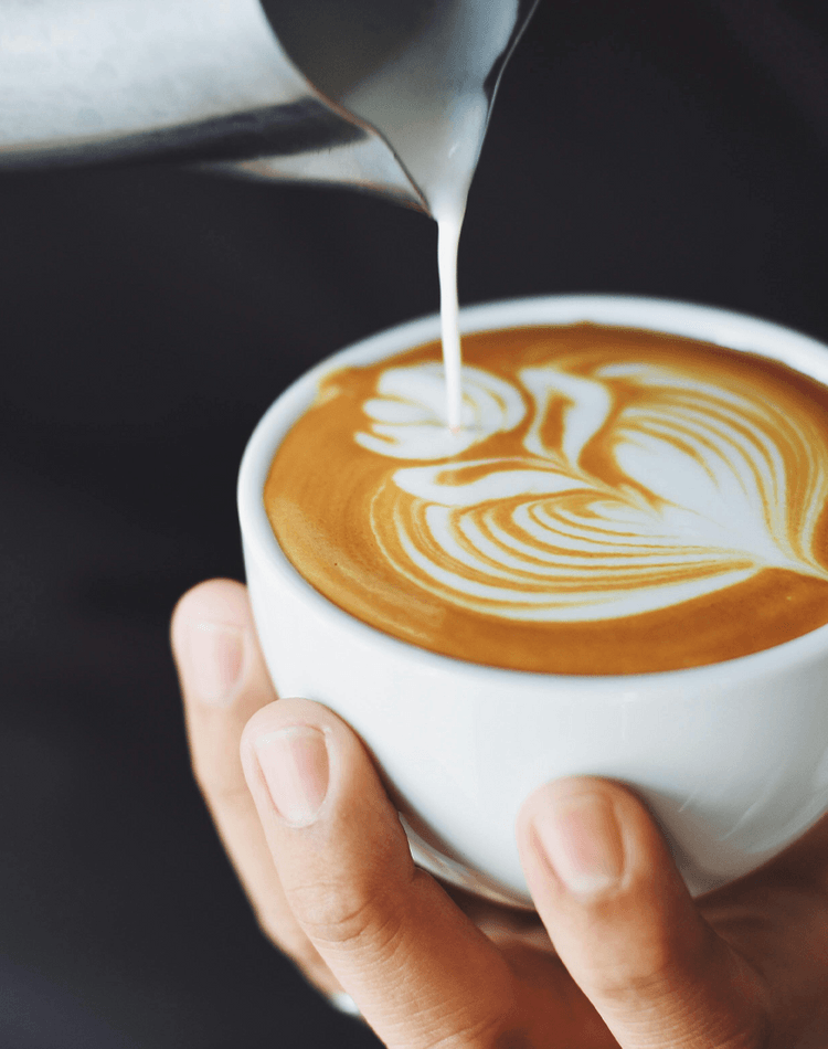 Frothed milk being poured into cup of coffee