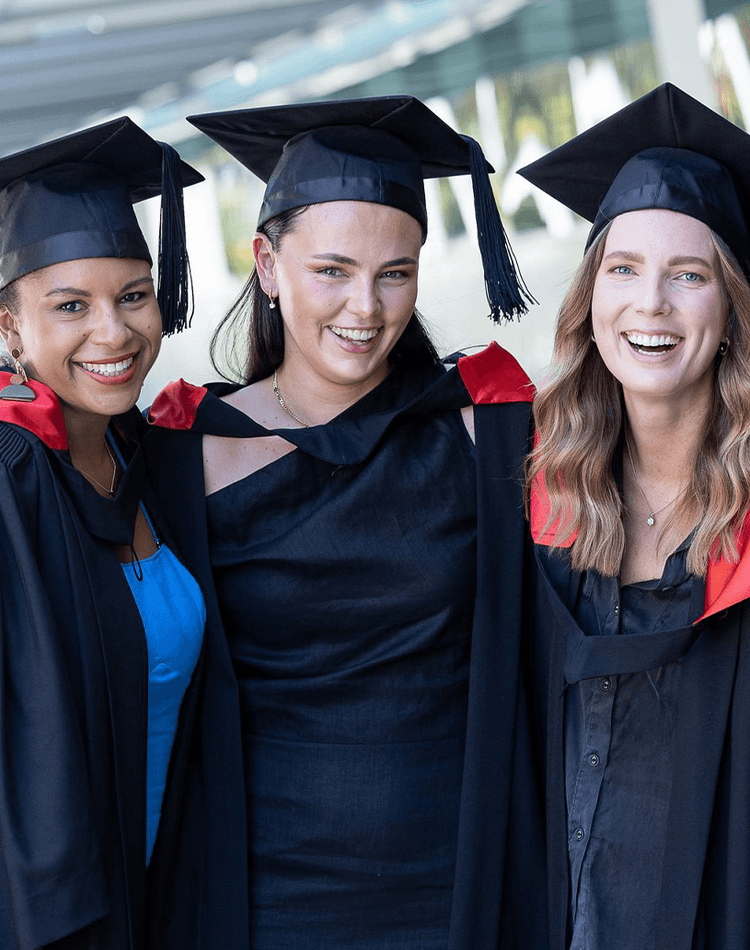 Group of students in graduation robes and mortarboards smiling at camera