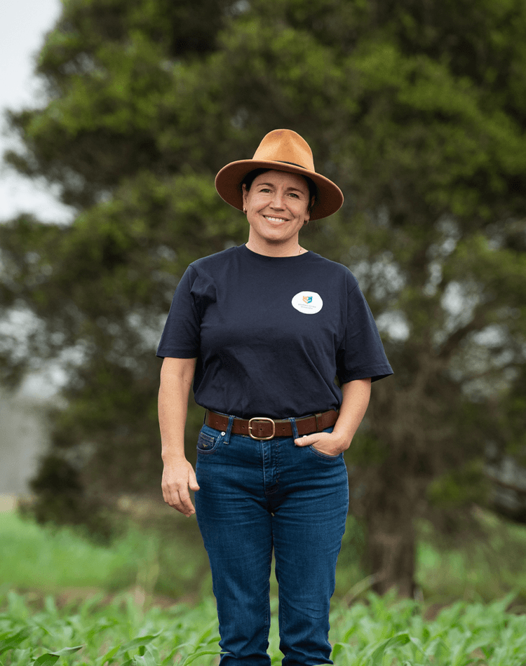 Hanabeth Luke in navy shirt and hat standing in crop field
