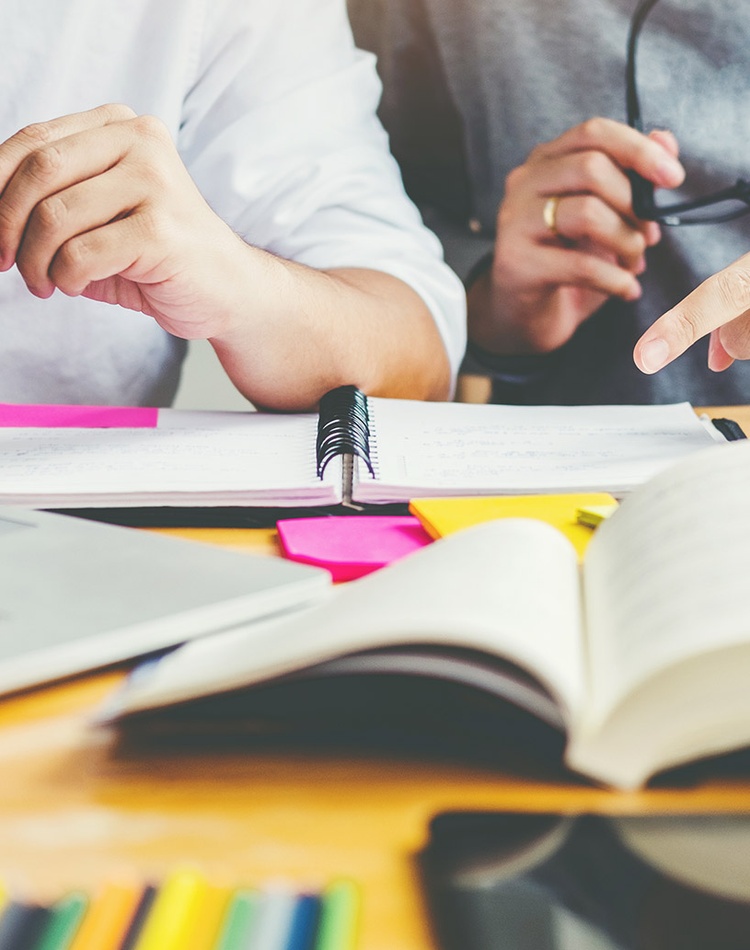 Researchers sitting at a desk with computer and books open