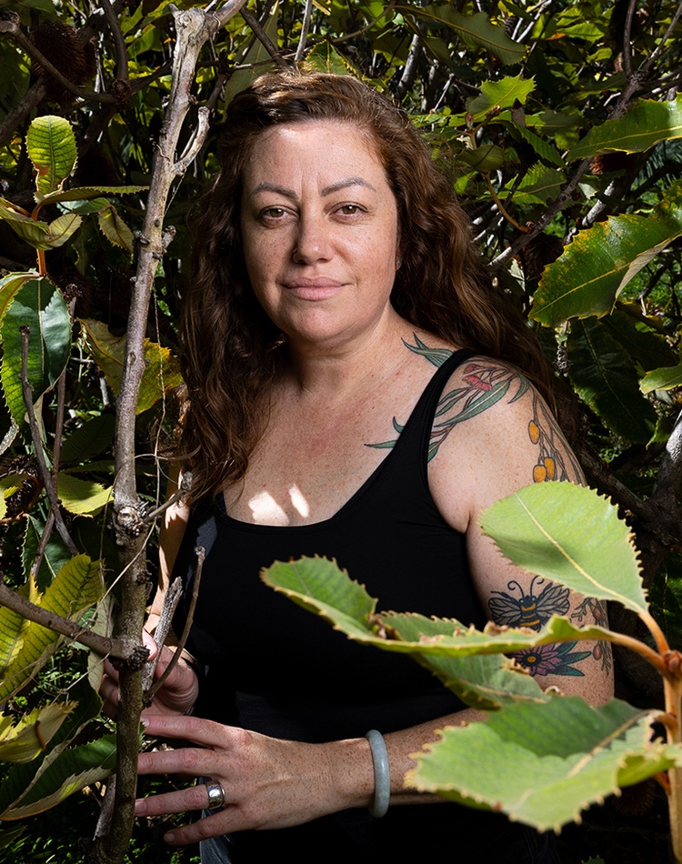 Woman with arm tattoos in a bush setting
