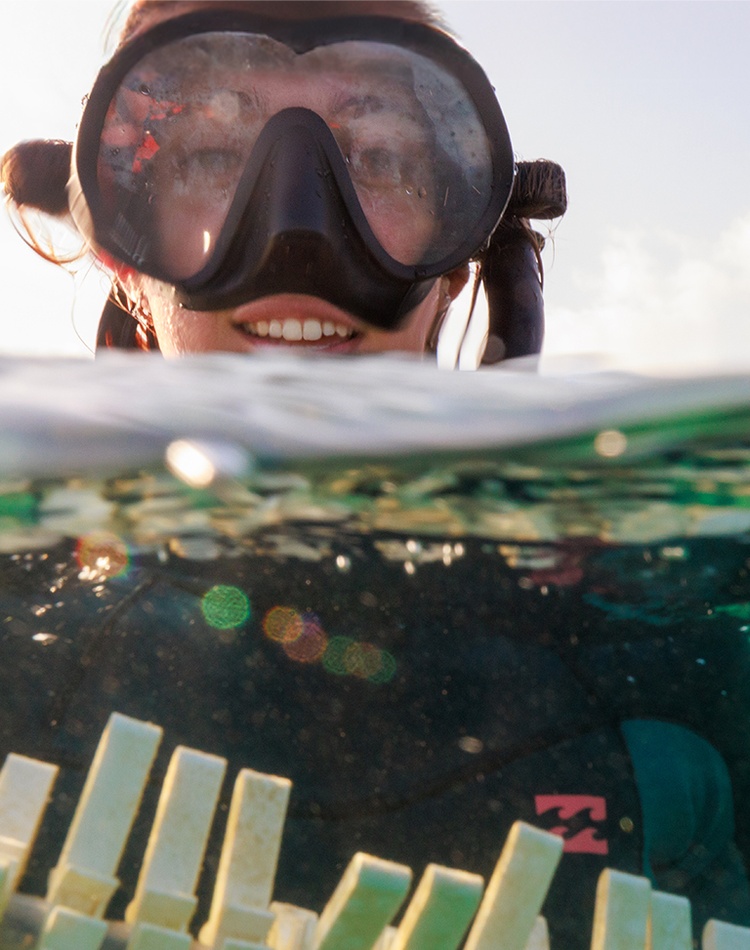 A woman in scuba diving gear holding a skewer of tiles
