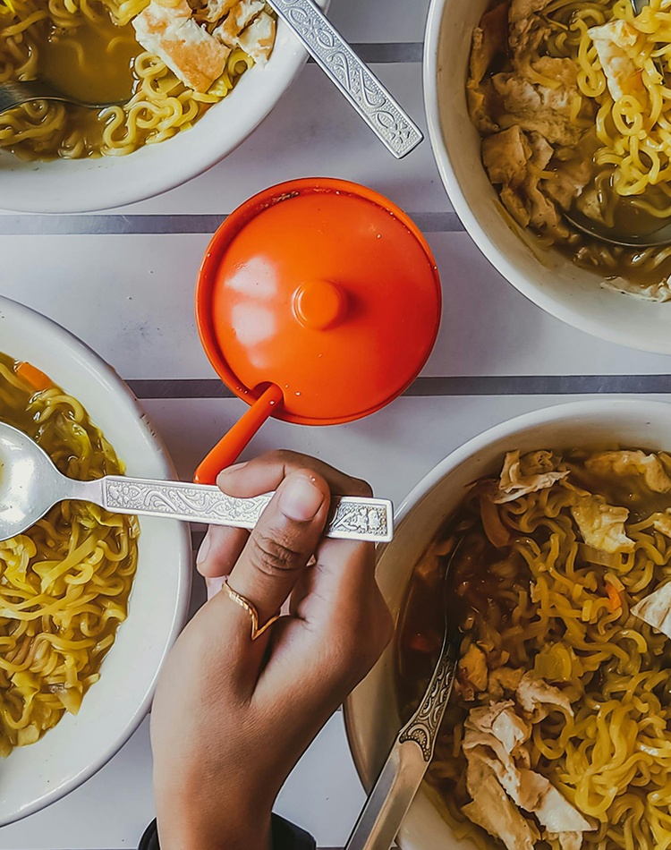 Close-up of a person getting noodles from four different bowls