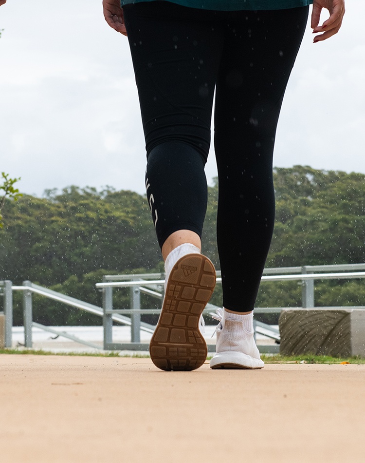 Close-up showing the legs and sneakers of three people walking