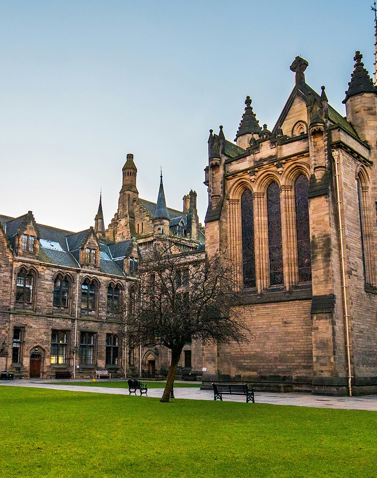 Exterior of a sandstone university with a grass lawn