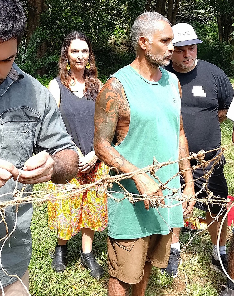 Indigenous men making a net using plant fibres