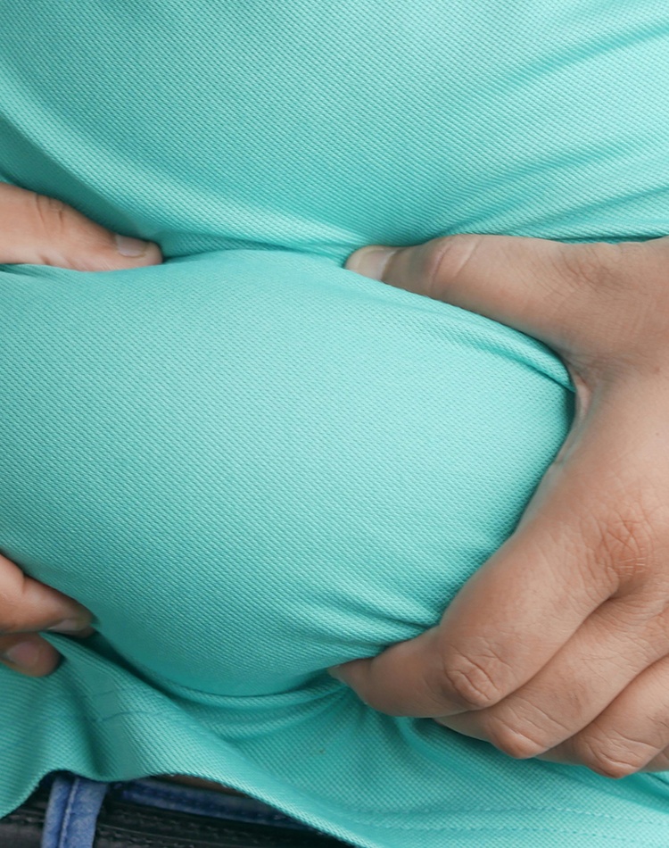 An overweight man holding excess skin in his belly