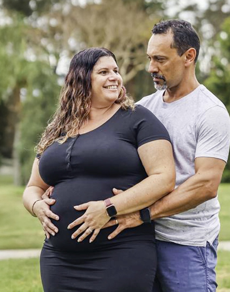 A pregnant woman being hugged by a man