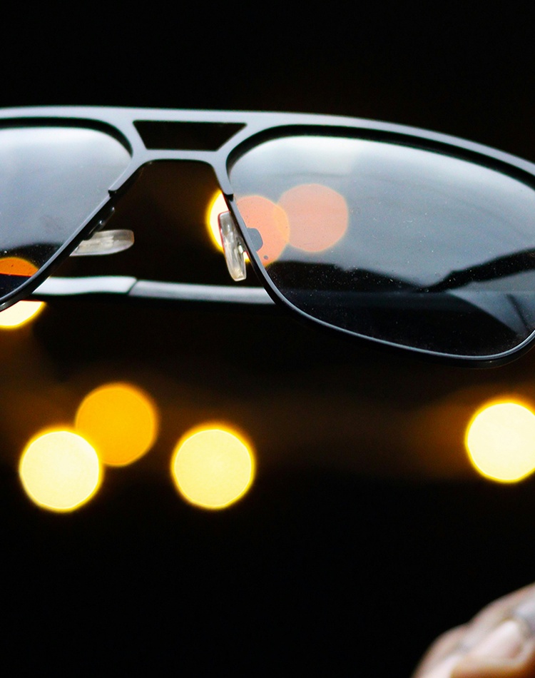 A black set of sunglasses held in a person's hand