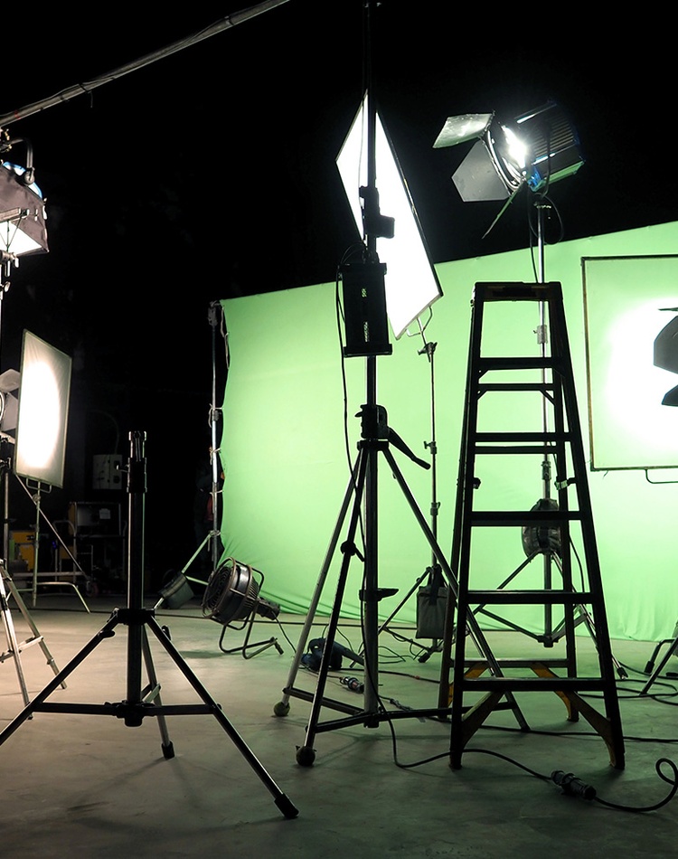 video services film setup with green screen lights camera person and cameras in silhouette