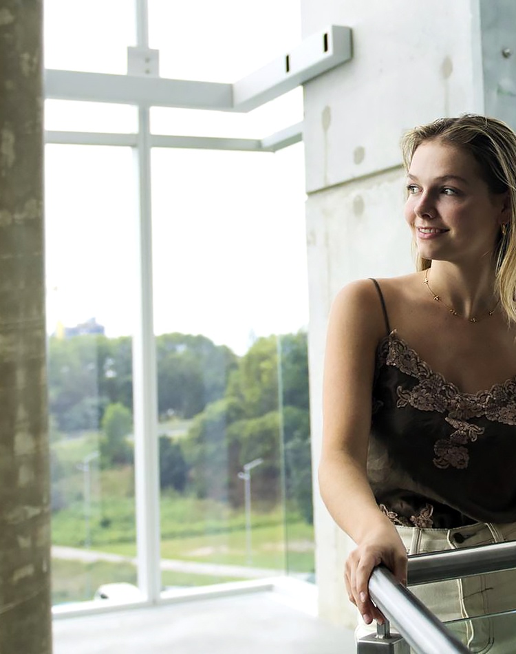 Student Lucia Miles stands on the stairs looking out the window at the Gold Coast campus