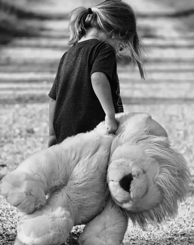 Girl holding plush toy on a dirt road