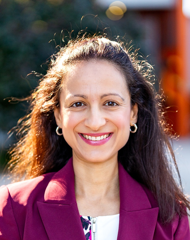 A woman standing on a campus looking at the camera