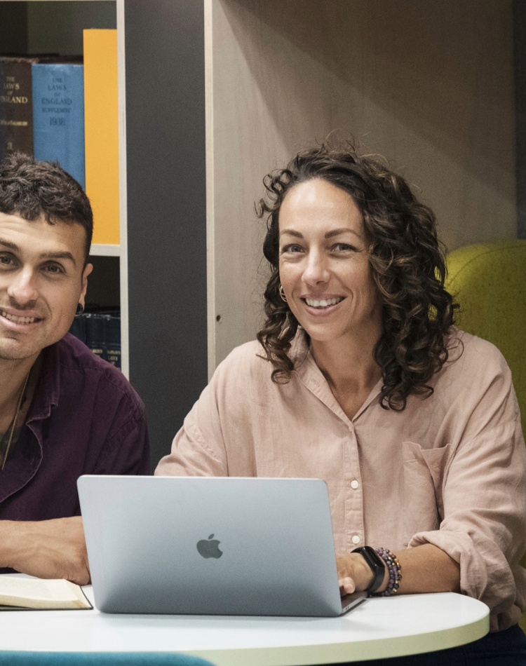 Two people at desk with laptop