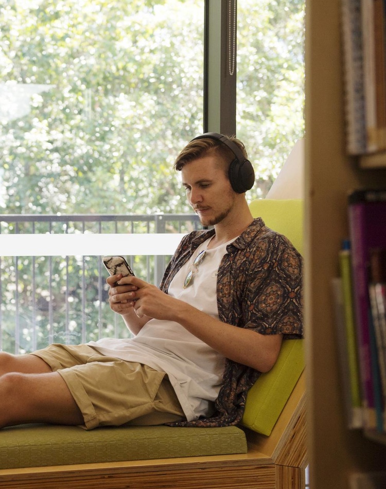 male relaxing on bench in library