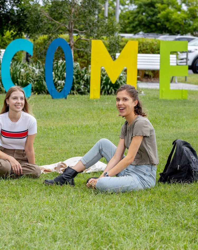 A group of students sitting near the welcome sign