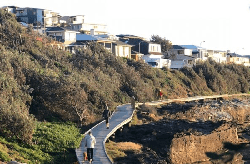 A timber walkway near houses alongside a cliff