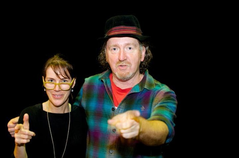 A man and woman smiling and pointing at the camera