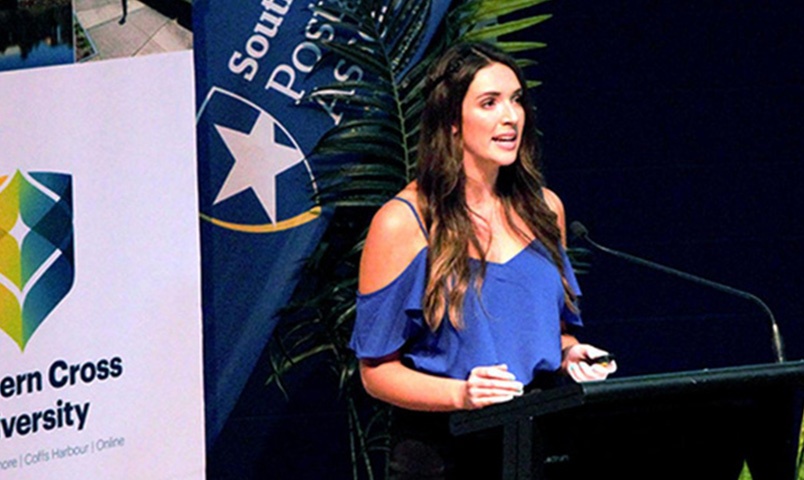 Rachel Clark, Psychology Honours student speaking at a podium at a Southern Cross Univeristy event for postgraduates