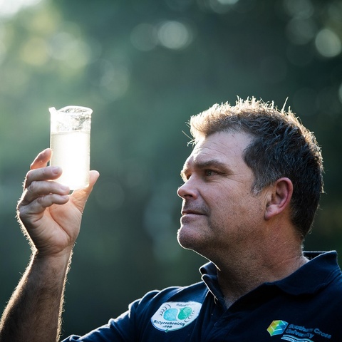 A man holds a beaker of water to the light