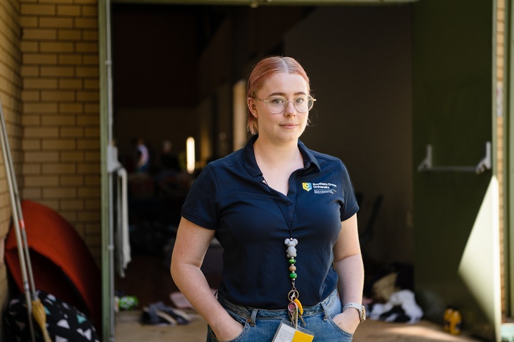 A woman looking at the camera in front of a large storage shed