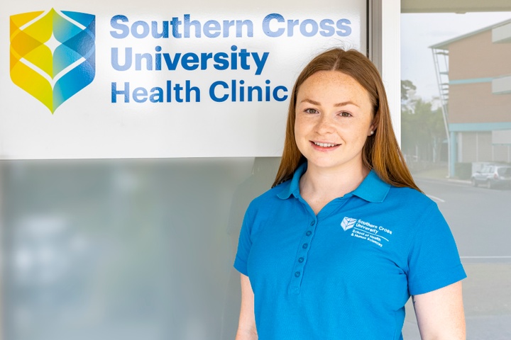 Student in blue polo standing in front of health clinic